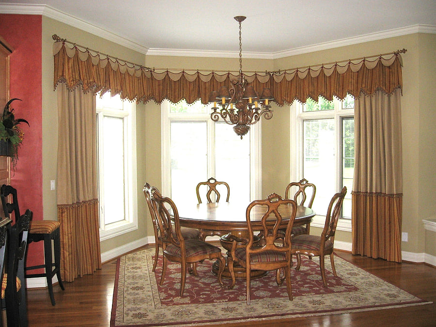 A dining room with swagged valances and floor-length draperies
