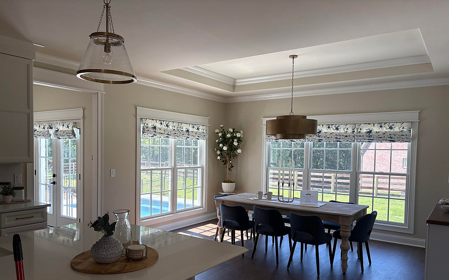 Roman shades across the kitchen windows and patio doors of an open-plan room