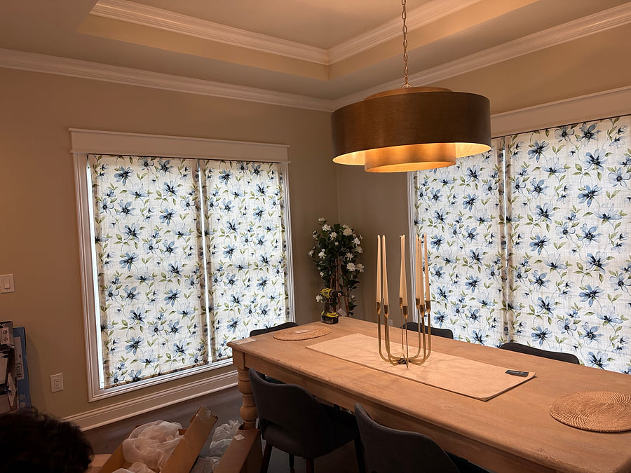 Kitchen roman shades lowered, with a pendant light above the island