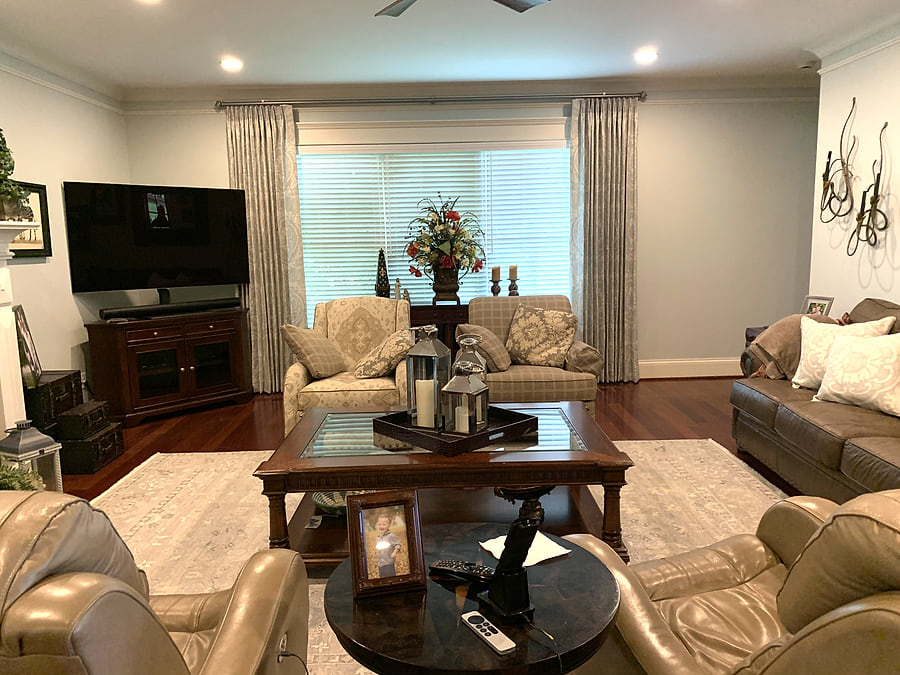 The same living room after a refresh, with new paint, furnishings, a custom rug and drapes
