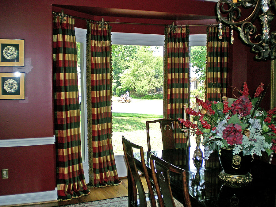 The same dining room window with full-length plaid drapes hung across it