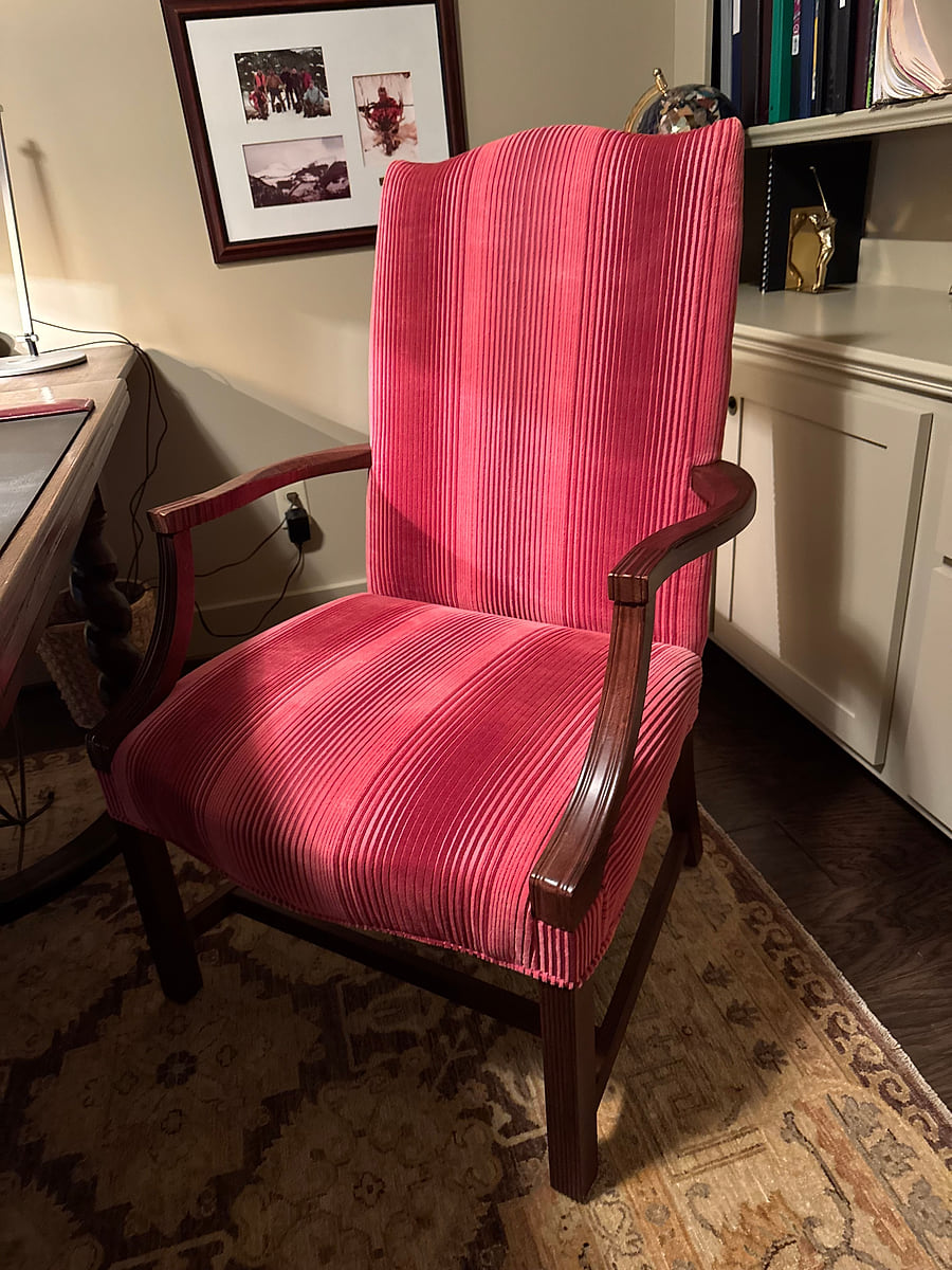 A wing chair reupholstered in a deep pink striped fabric