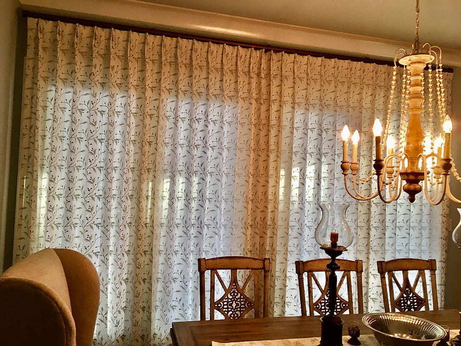 Embroidered sheer draperies drawn closed across a dining room window