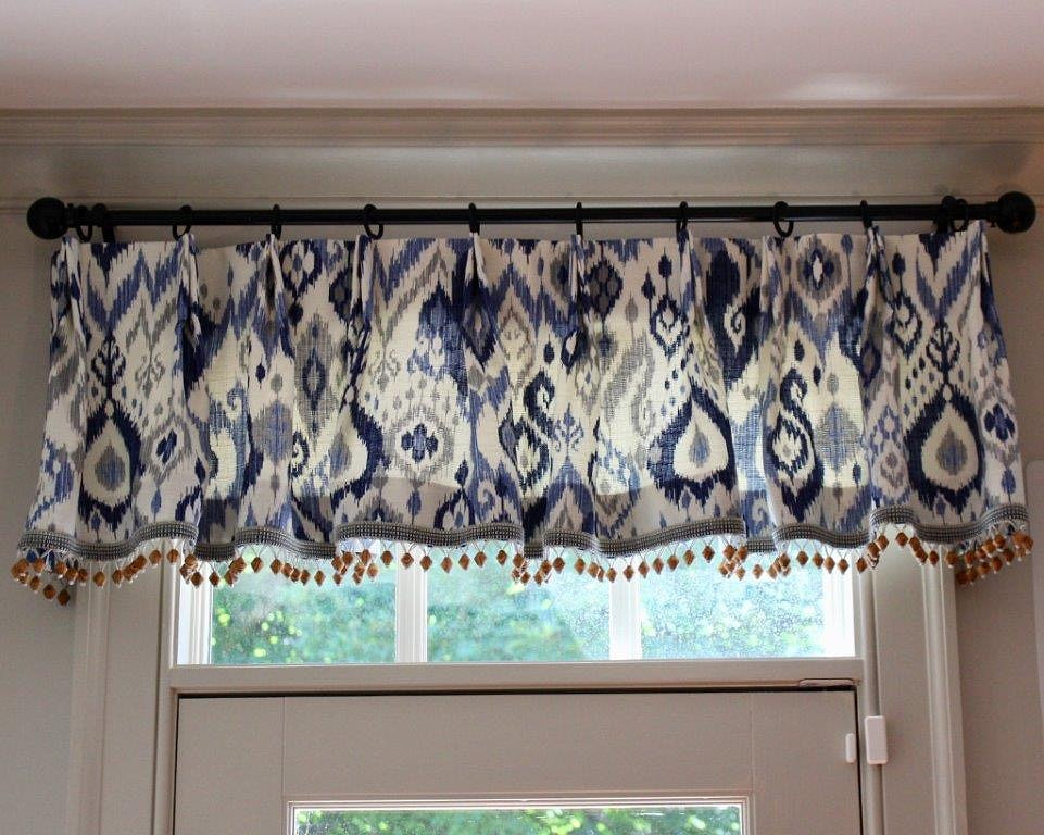 An upholstered cornice above plantation shutters in a bathroom