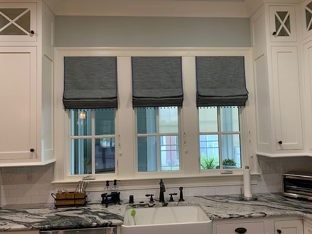 Three roman shades across a kitchen sink window